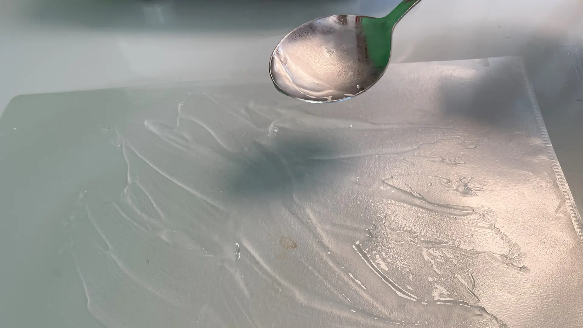 Spoon with gel-like mass is held over a foil on which the gel has been spread.