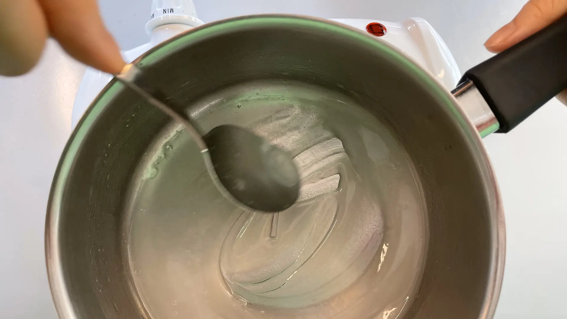 Small saucepan with starch mixture, which is stirred with a spoon.